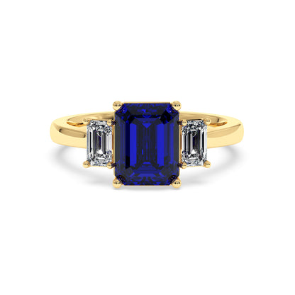 Elegant gold 3.5 carat blue sapphire ring with large rectangular gemstone and two smaller diamonds. Luxurious design.
