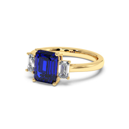 Elegant gold 3.5 carat blue sapphire ring with deep blue rectangular center gemstone and two smaller clear diamonds.