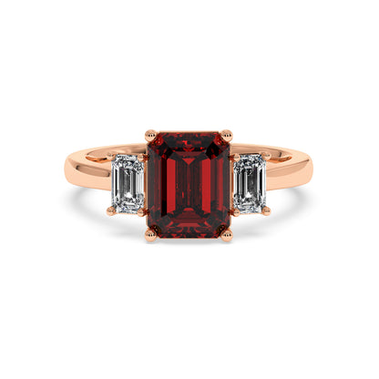 Rose gold 3.5 carat emerald cut ring with red center stone and two side diamonds. Elegant design.