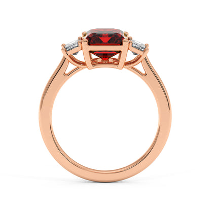 Elegant rose gold 3.5 carat emerald cut ring with red gemstone and two smaller white stones.