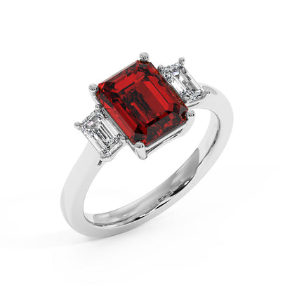 Top view of 14k white gold 3.5 carat emerald cut ring with red gemstone and two smaller clear stones.