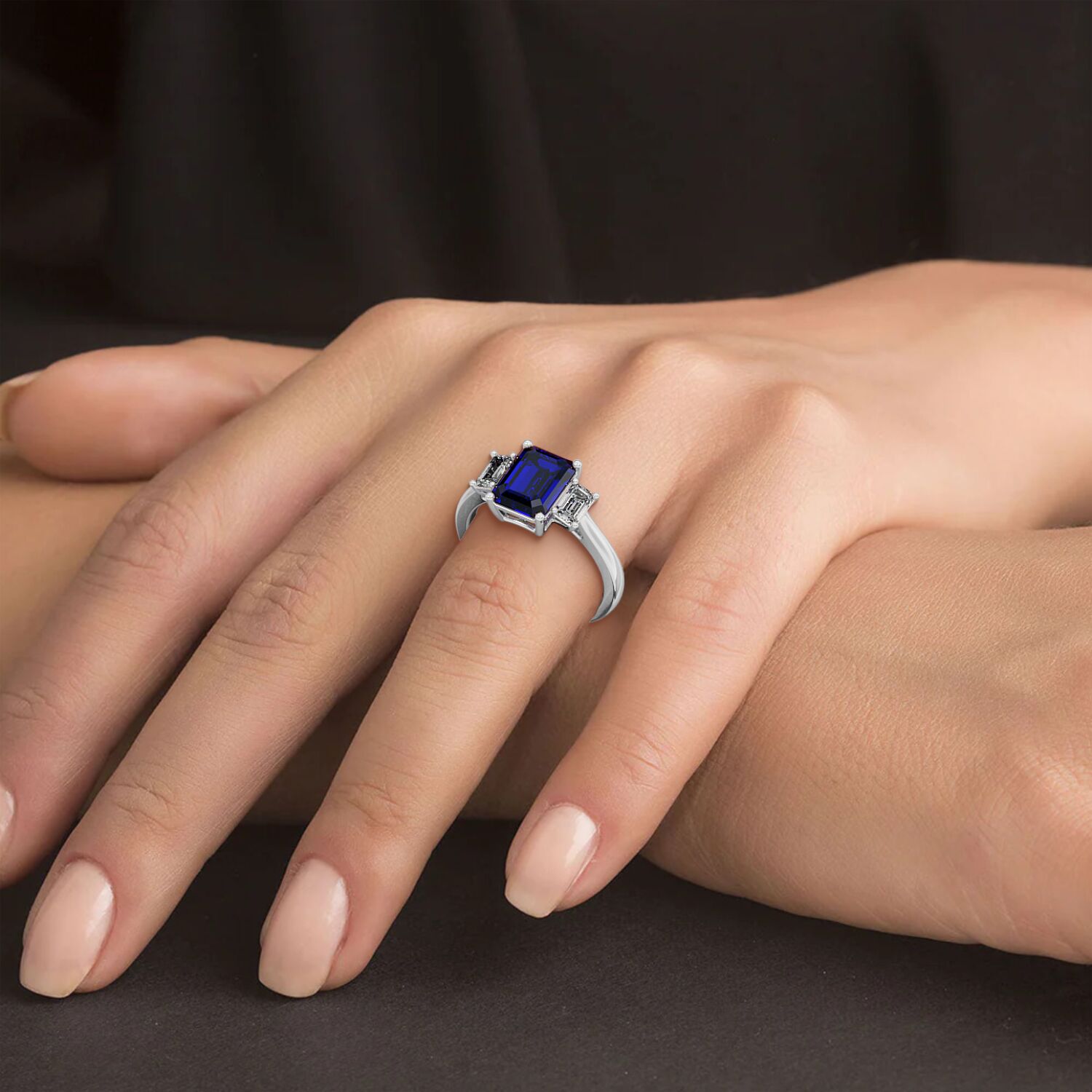 Hand wearing a 14k white gold 3.5 carat blue sapphire ring with deep blue square gemstone. Luxurious design.