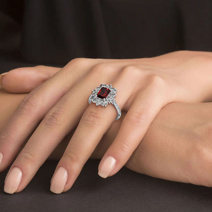 A hand wears a 14k white gold ring featuring a 2.25CT red ruby surrounded by small diamonds, showcasing timeless elegance.