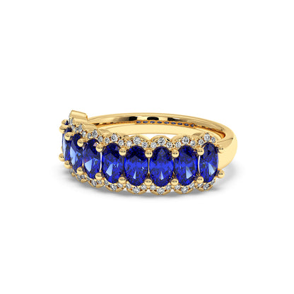 14k gold ring with a row of vivid Blue Sapphire oval gemstones, bordered by small sparkling diamonds.