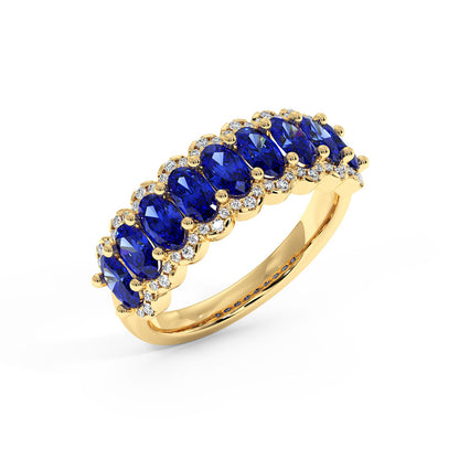 14k gold ring with a row of vivid blue oval sapphires, each bordered by small sparkling diamonds.