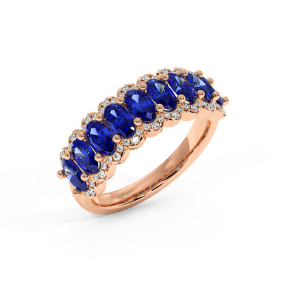 Luxurious 14k rose gold ring adorned with a row of oval blue sapphires, each surrounded by small sparkling diamonds.