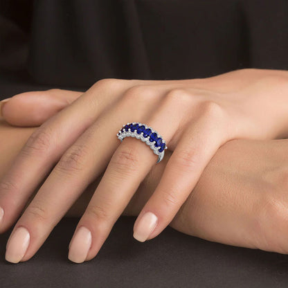 Close-up of a hand resting on a surface, wearing a 14k white gold ring with large, dark Blue Sapphire gemstones.