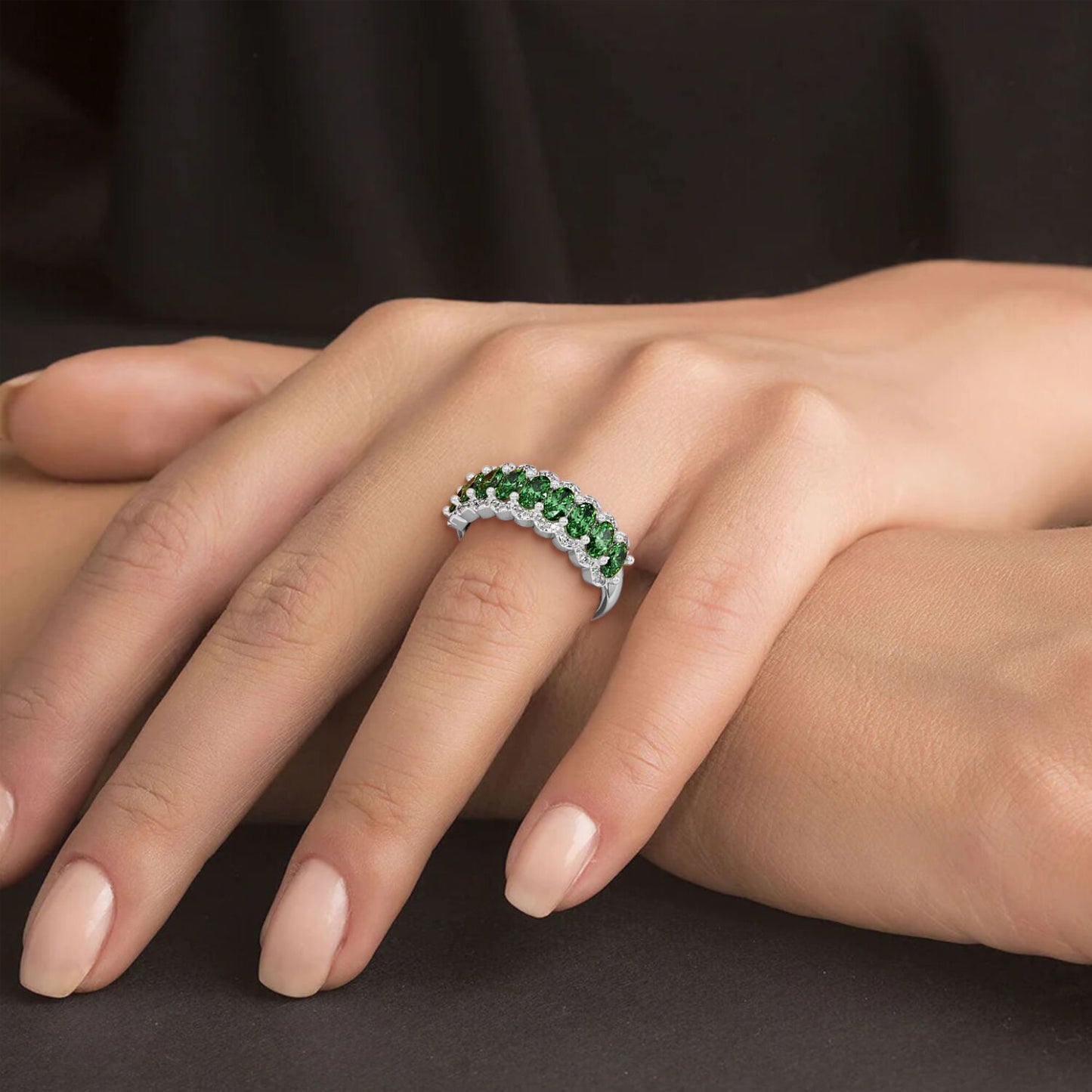 14k white gold ring featuring bright Green YAG stones, worn on a manicured hand resting on a dark surface.