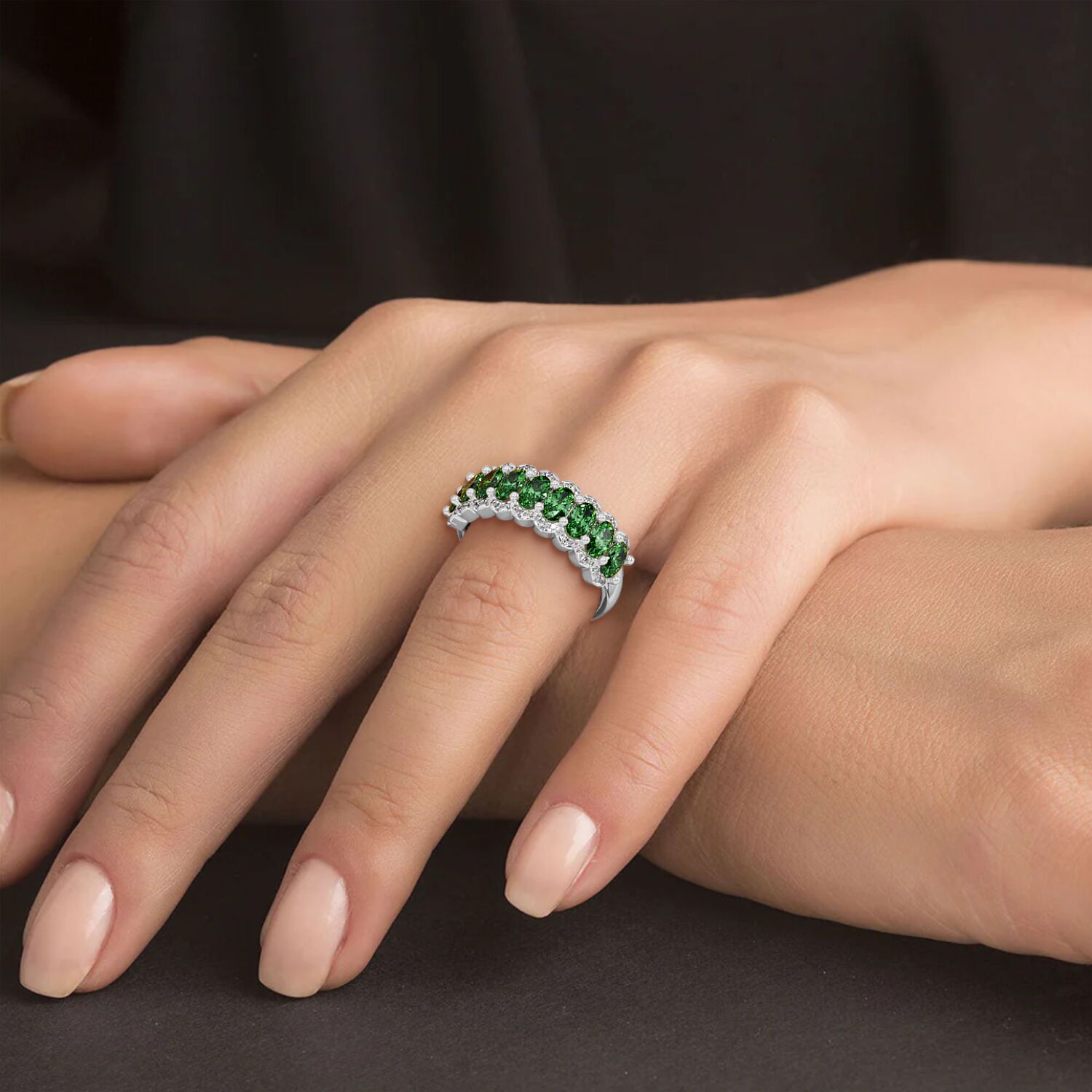 14k white gold ring featuring bright Green YAG stones, worn on a manicured hand resting on a dark surface.