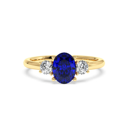 Gold ring with an oval deep blue sapphire flanked by two round diamonds, showcasing an elegant design that exudes luxury and sophistication.