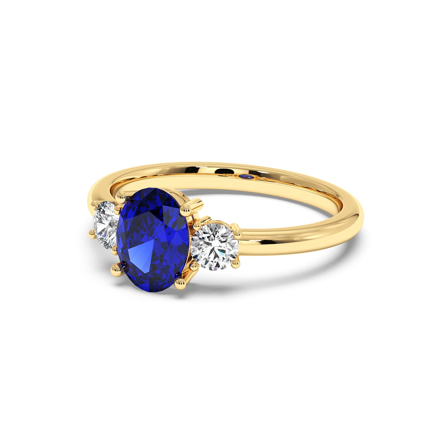 Gold ring with an oval blue sapphire center and two round white diamonds on each side, set against a white background.