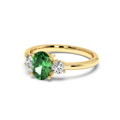 A gold ring with an oval green Y.A.G in the center, flanked by two round white diamonds. The design is elegant and luxurious.