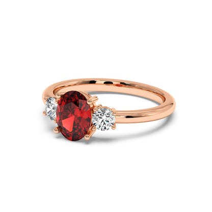 Rose gold 1.75 CT oval ruby ring with red center gemstone flanked by two round white diamonds. Elegant, luxurious design.