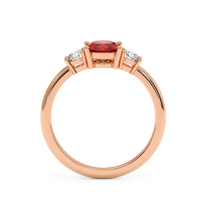 Rose gold 1.75 CT oval ruby ring with central round red gemstone and two smaller diamonds. Elegant, luxurious design, white background.