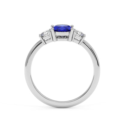14k white gold ring with an oval blue sapphire center flanked by two round diamonds on a white background, showcasing elegant design.