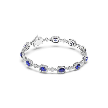 A 14k white gold bracelet featuring alternating oval blue sapphire gemstones and small round diamonds in an elegant pattern.