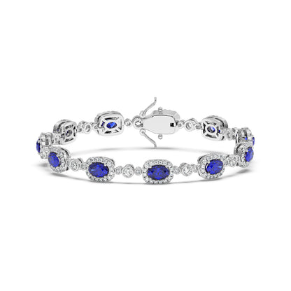 Elegant 14k white gold bracelet with oval blue sapphire gemstones framed by small white diamonds.