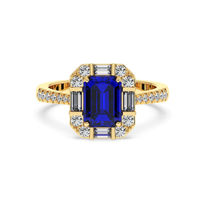 14k gold ring with a deep blue emerald-cut sapphire framed by round and baguette diamonds, exuding elegance and luxury on a white background.