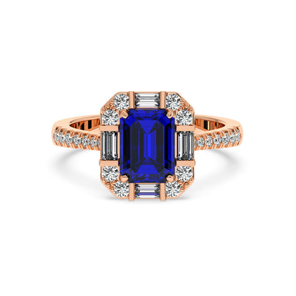 A rose gold emerald ring with a large blue sapphire center surrounded by sparkling diamonds on the band, exuding elegance and luxury.