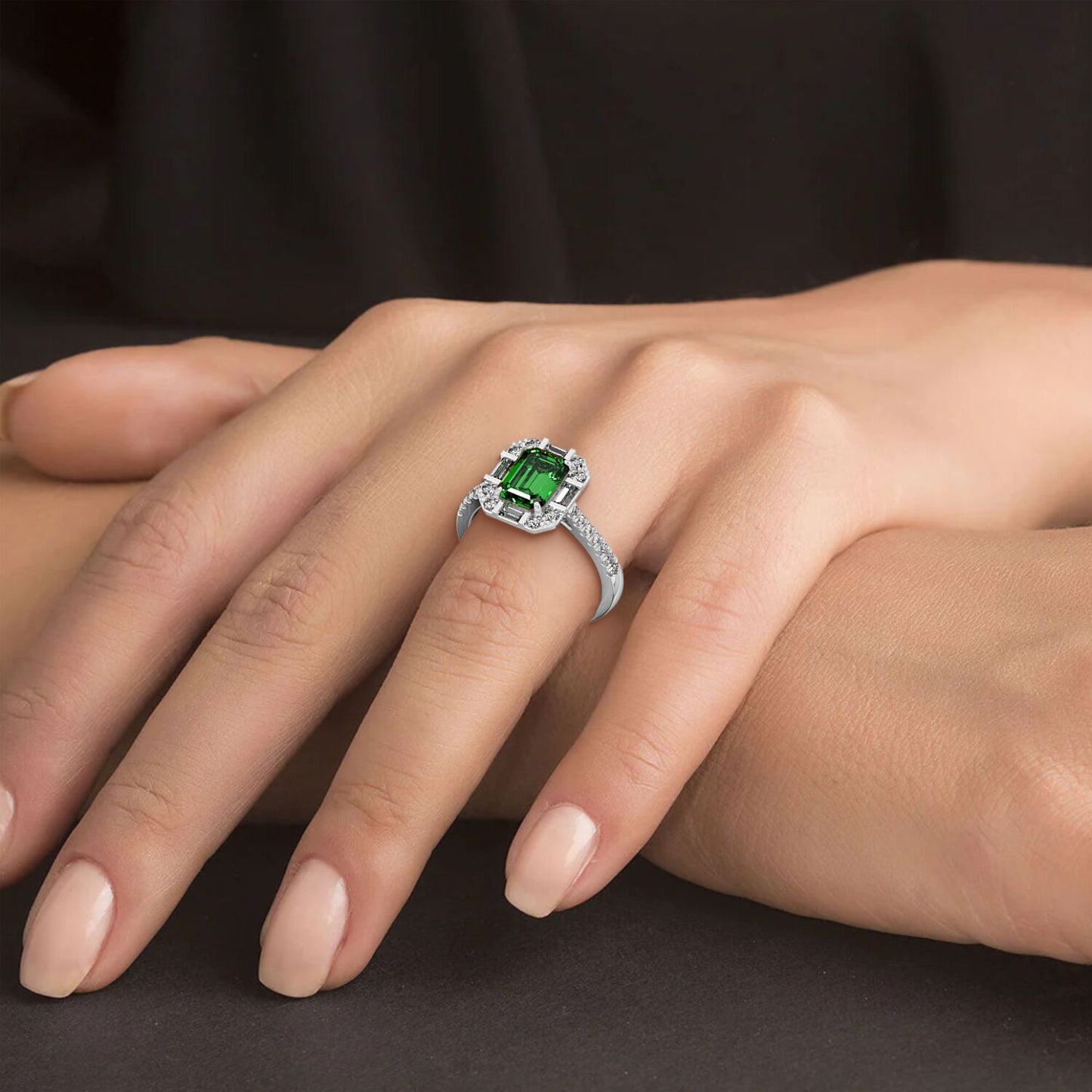 A hand showcases a 14k white gold ring with a large green YAG center surrounded by small diamonds, set against a dark background.