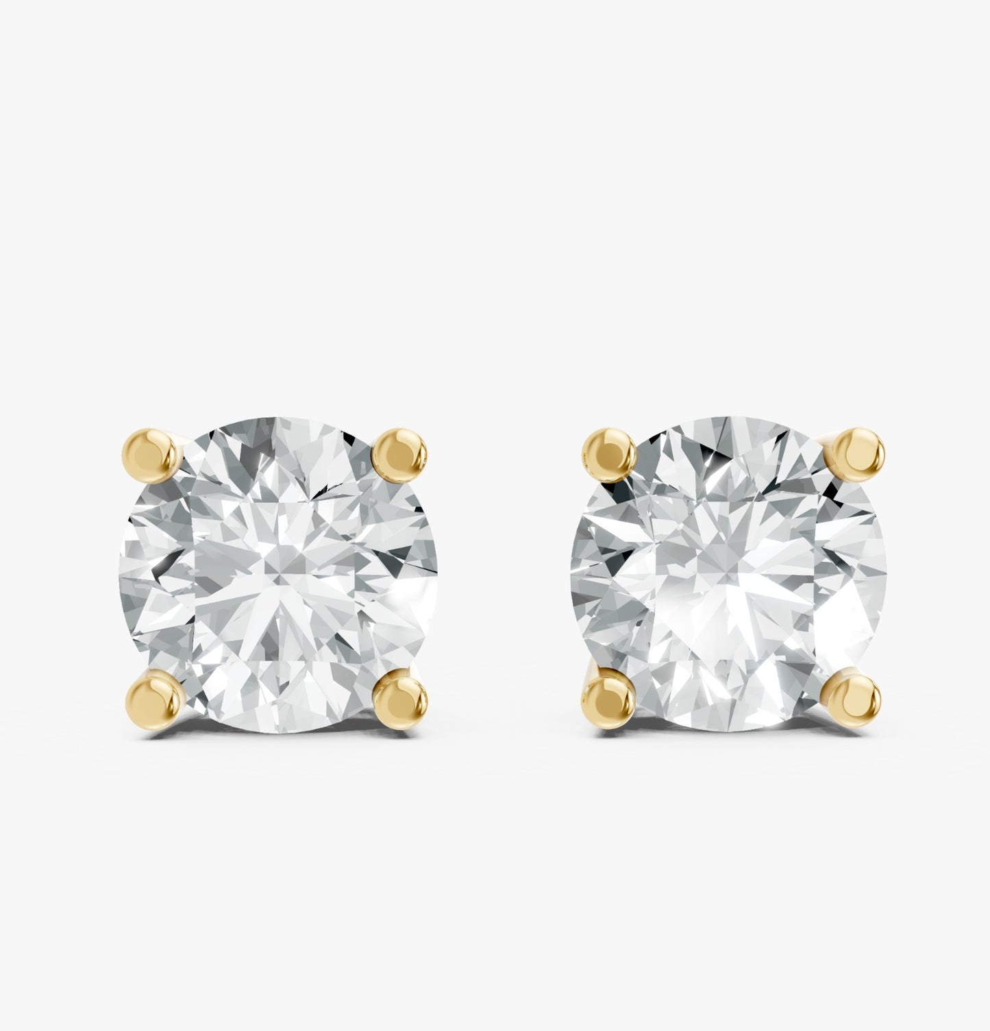 A pair of dazzling round diamond stud earrings are set in Gold plated prongs on a white background.