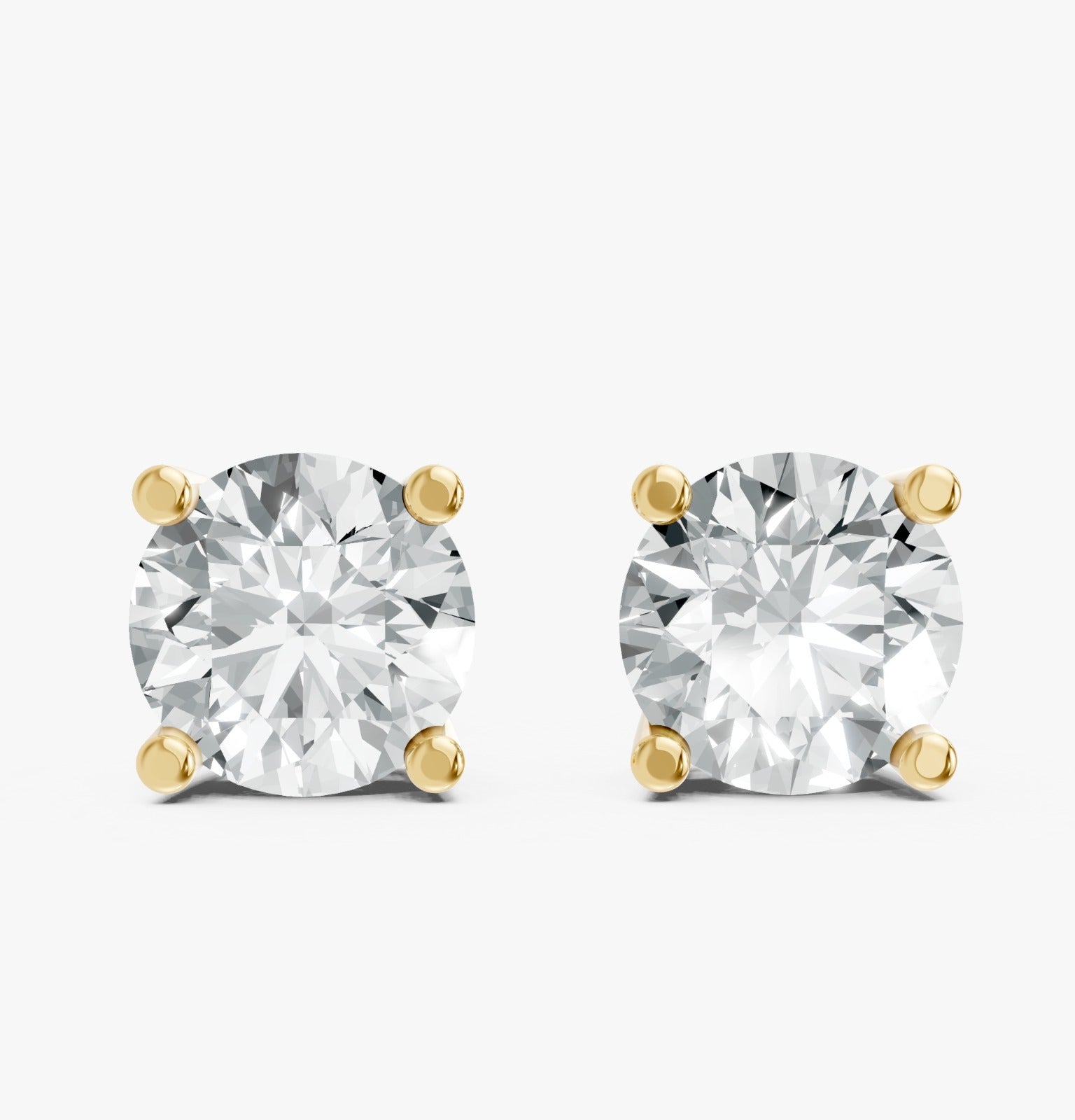 A pair of dazzling round diamond stud earrings are set in Gold plated prongs on a white background.